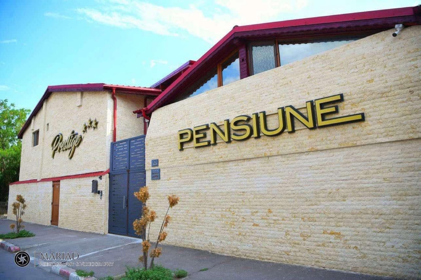 Fațada Pensiunii Prestige din Roșiori de Vede, cu firma PENSIUNE pe peretele de piatră